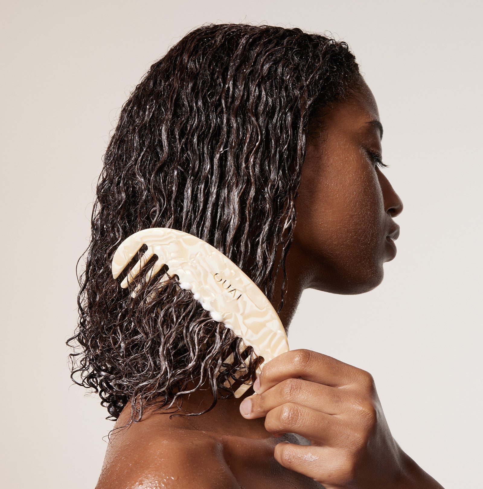 woman combing her wet and black curly hair 
