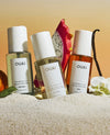 3 of ouai hair and body mist bottles on a orange background