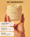 Jar of OUAI body cream held by a hand with key ingredients listed on a yellow background