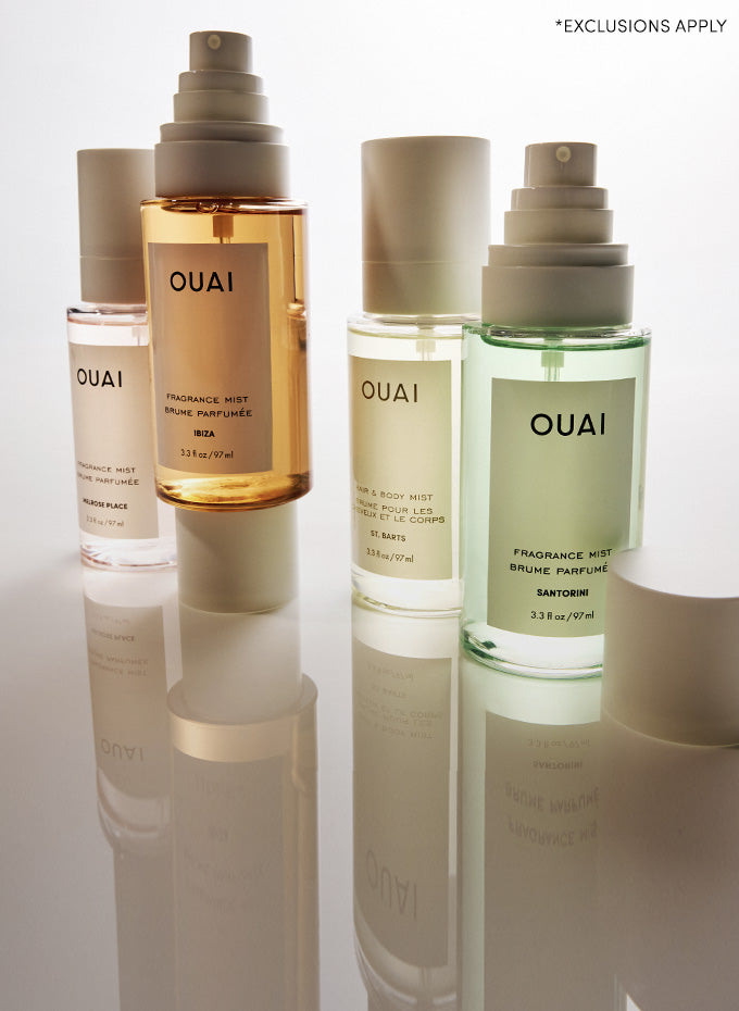 OUAI hair care products including bottles and a spray bottle on a reflective surface.