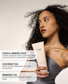Woman holding an OUAI product with hair care benefits text overlay