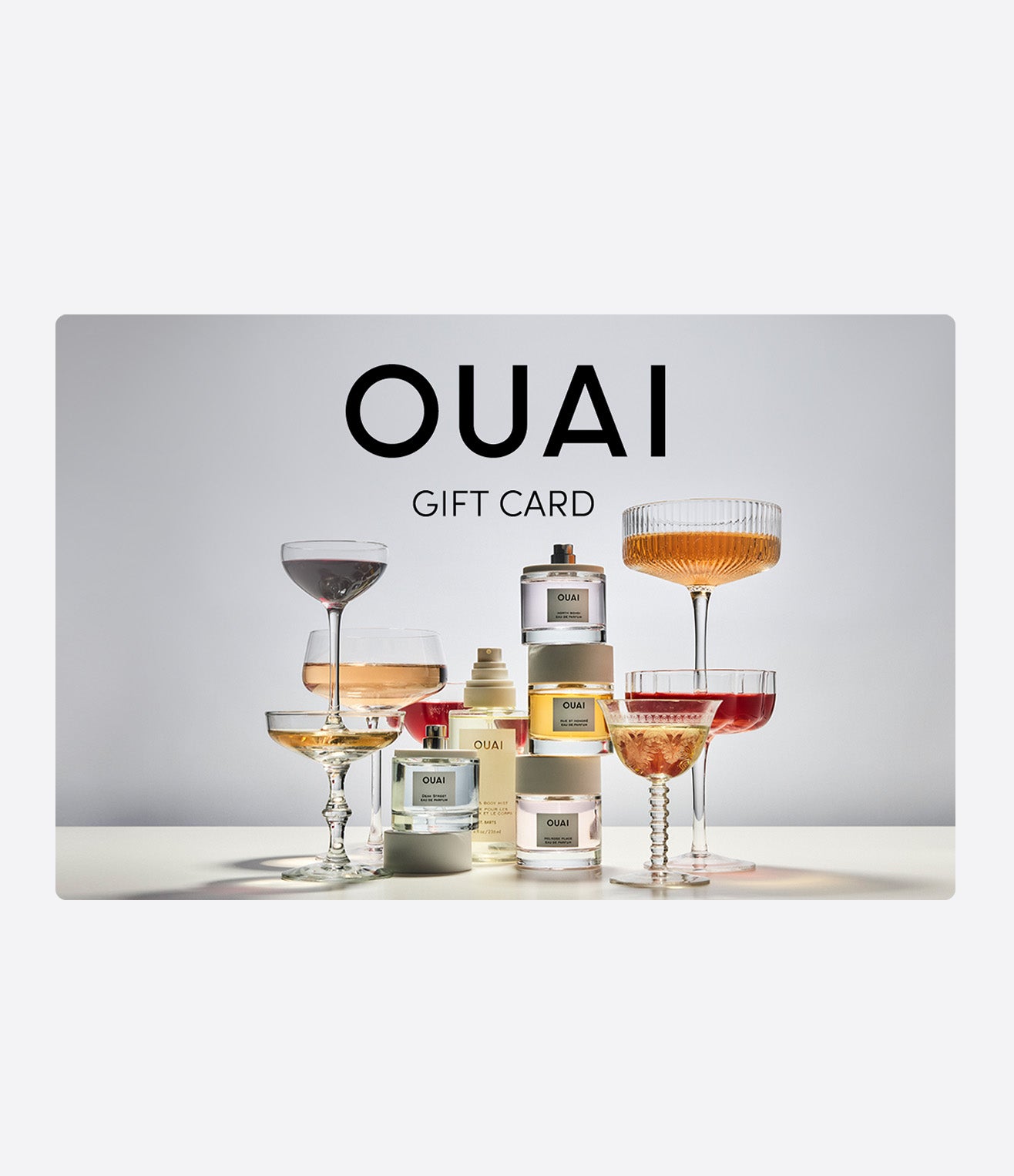 OUAI Gift Card featuring perfume bottles and elegant cocktail glasses on display.