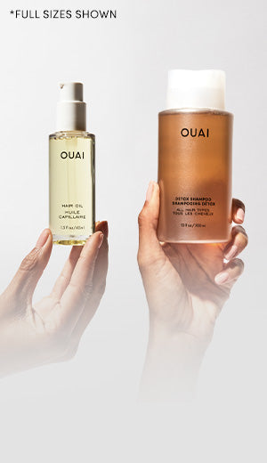 Two OUAI hair care products held by hands against a white background