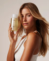 Woman holding a OUAI product against a neutral background