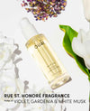 OUAI hair oil bottle with flowers and leaves on a light background