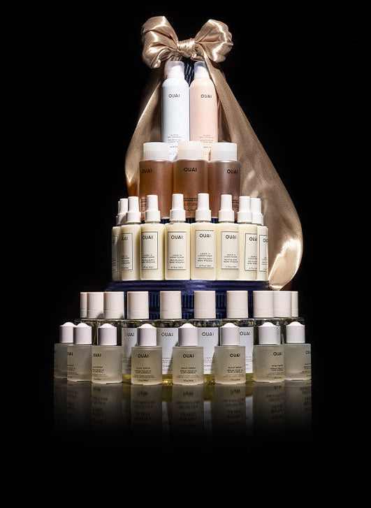 Tower of skincare bottles with a gold bow on a black background