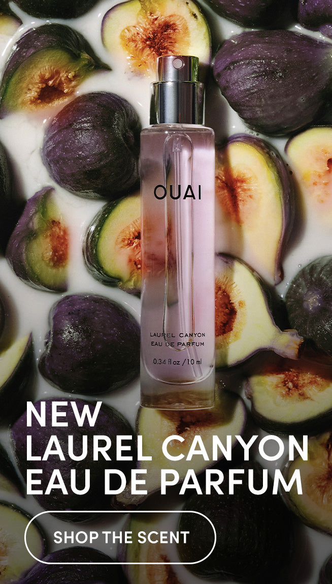 A clear OUAI Laurel Canyon bottle with pale pink liquid, centered among sliced purple figs and creamy white background.