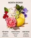 A fragrance notes graphic for North Bondi, featuring a styled arrangement of fresh ingredients and flowers including a pink rose, yellow lemon, limes, raspberries, white flowers, and purple violets on a light beige background. Text below lists top, middle, and base notes.