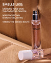 Two clear perfume spray bottles labeled OUAI placed on a tan leather surface, with white text on the left reading 'SMELLS LIKE: CRUISE YOUR OUAI THROUGH THE CANYON WINDOWS DOWN & RADIO'S BLASTING TAKING THE SCENIC ROUTE'.