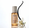 OUAI fragrance mist bottle with a vanilla bean and white flower on a white background