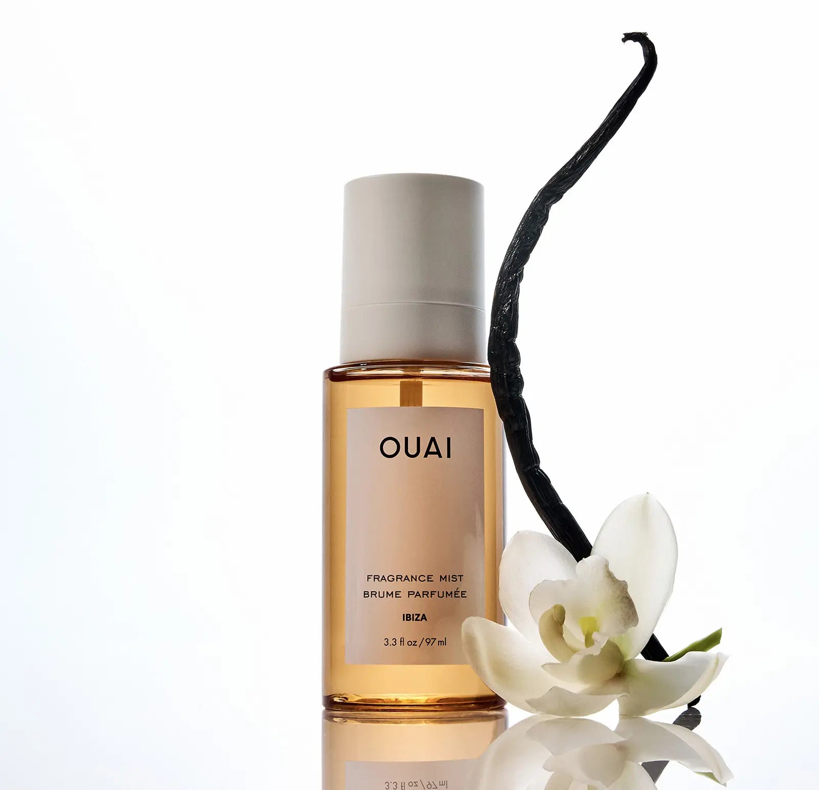 OUAI fragrance mist bottle with a vanilla bean and white flower on a white background