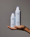 Two OUAI Super Dry Shampoo bottles shown side by side on a dark background