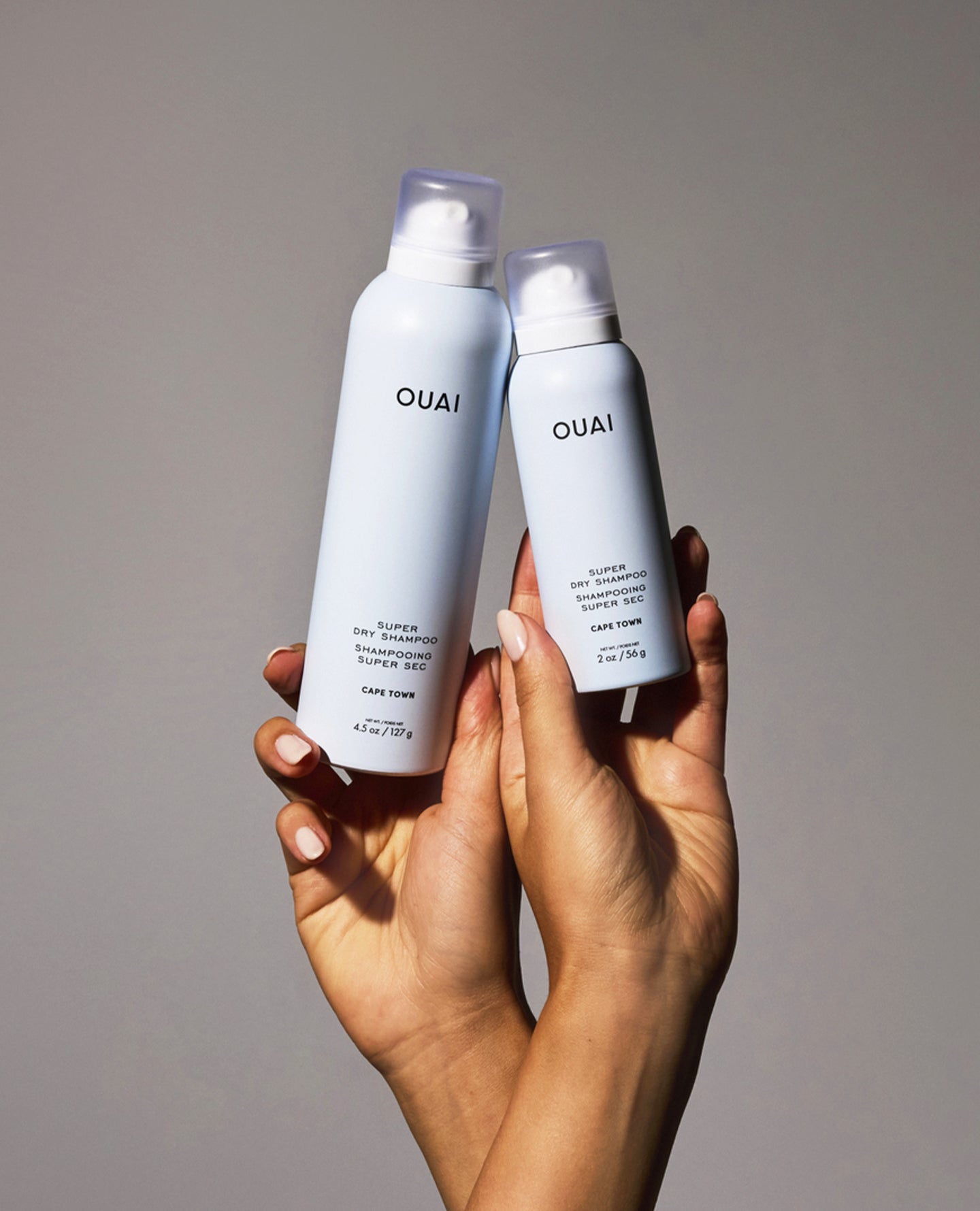 Two OUAI Super Dry Shampoo bottles shown side by side on a dark background