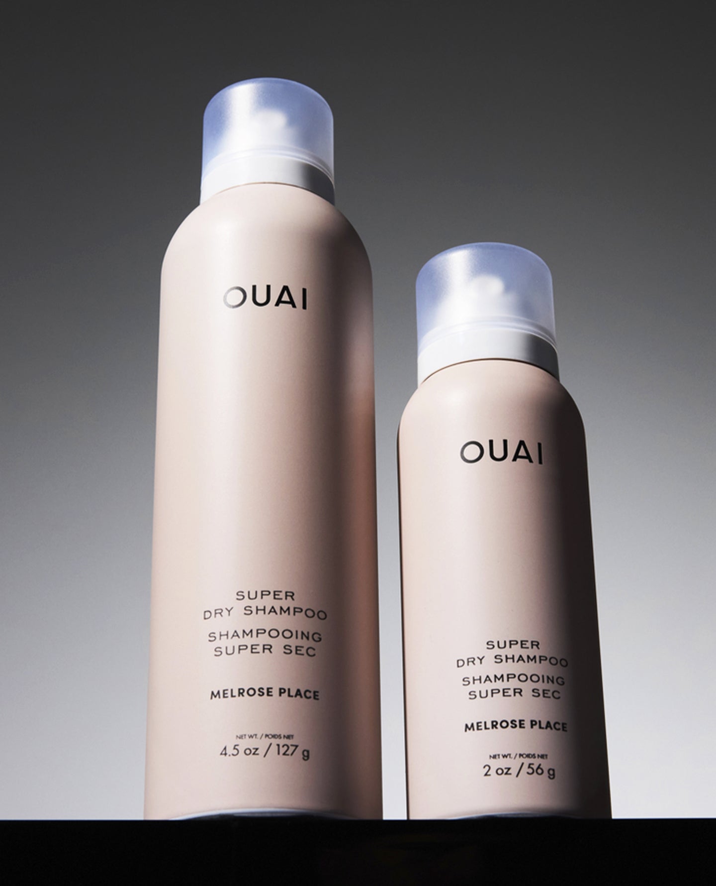 Two OUAI Super Dry Shampoo bottles shown side by side on a dark background