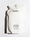 A white stand-up pouch of OUAI Thick Hair Conditioner with black text, photographed on a white background with a strong cast shadow.