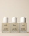 Three identical frosted OUAI Scalp Serum bottles stand side by side on a cream surface, presenting a 90-day supply beneath white applicator caps.
