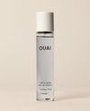 A slim travel perfume bottle containing pale blue liquid stands upright against a softly lit cream backdrop. Text: “OUAI”, “NORTH BONDI”, “EAU DE PARFUM”, “0.34 fl oz / 10 ml”.