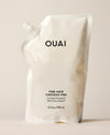 A white OUAI Fine Hair Shampoo refill pouch stands upright on a warm cream studio surface. Text: “OUAI”, “FINE HAIR”, “CHEVEUX FINS”, “SHAMPOO”, “SHAMPOOING”, “32 fl oz / 946 ml”.