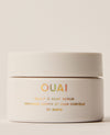 A wide ivory OUAI St. Barts Scalp & Body Scrub jar sits on a cream studio surface, finished with iridescent branding and a large matching lid.
