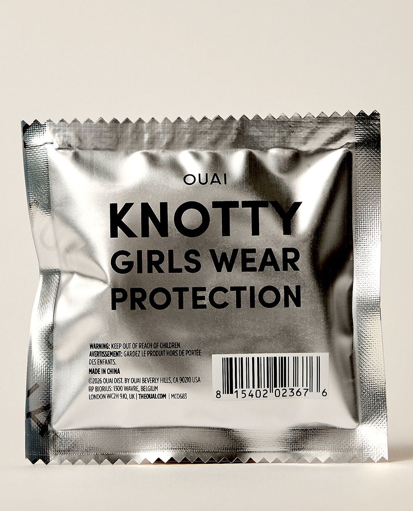 OUAI Knotty Girls Wear Protection silver foil hair tie packet on neutral background
