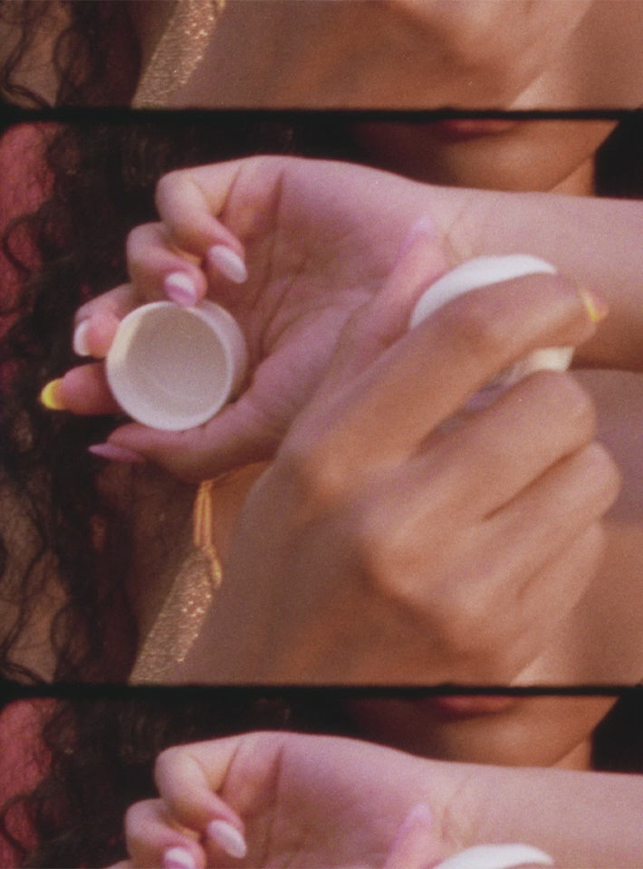 female model holding St. Barts solid perfume and rubbing perfume on her neck and wrists