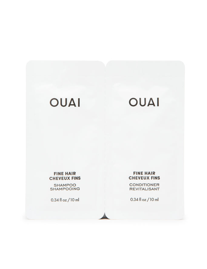 Two packets of Ouai fine hair shampoo and conditioner designed for travel, with white packaging and branding visible.